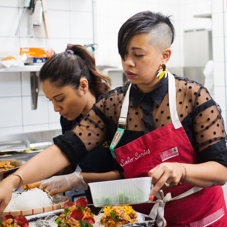 Two people cooking and preparing dishes in a kitchen.