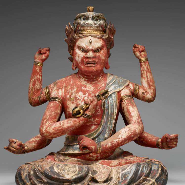 Six-armed, angry-faced, red-skinned deity.
