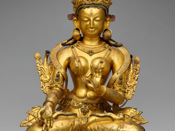 Gilded, crowned and bejeweled female figure, seated in lotus position.