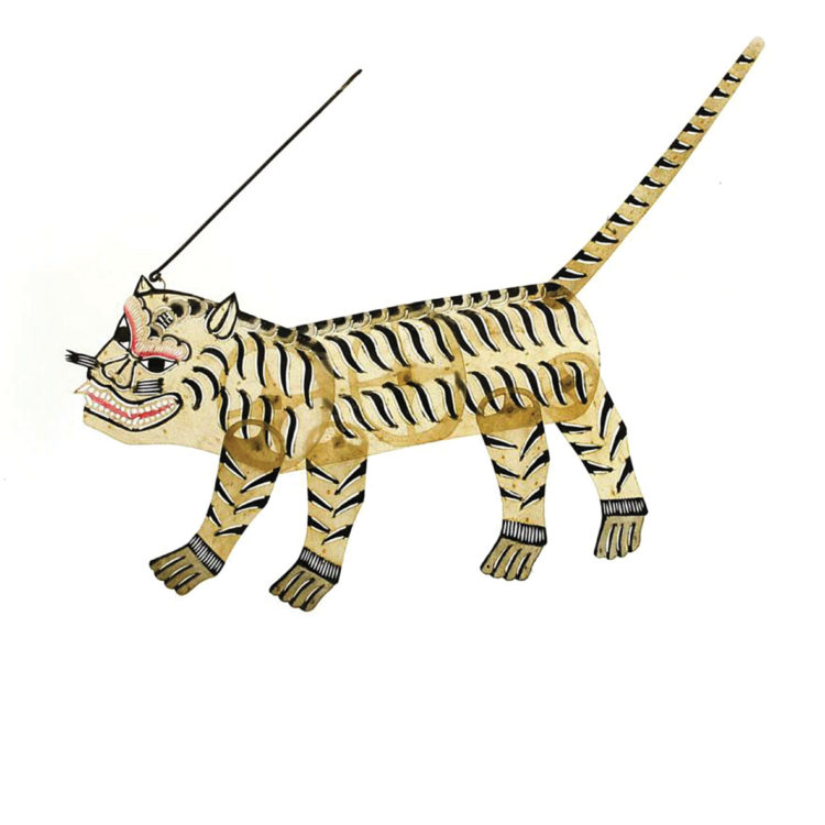 Small, semi-translucent puppet in the shape of a tiger. Light yellow with thin black stripes and a long, pointy tail.  