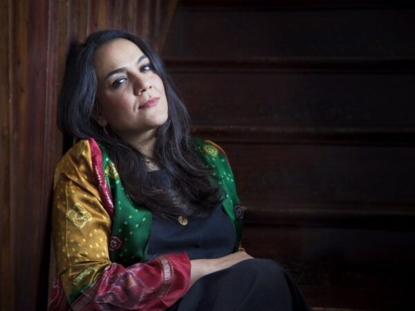 Marjan Vahdat leans against a wall in a colorful Persian blouse.