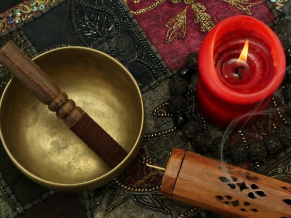 A photographic collage of a singing bowl, candle and textiles used in sound healing.
